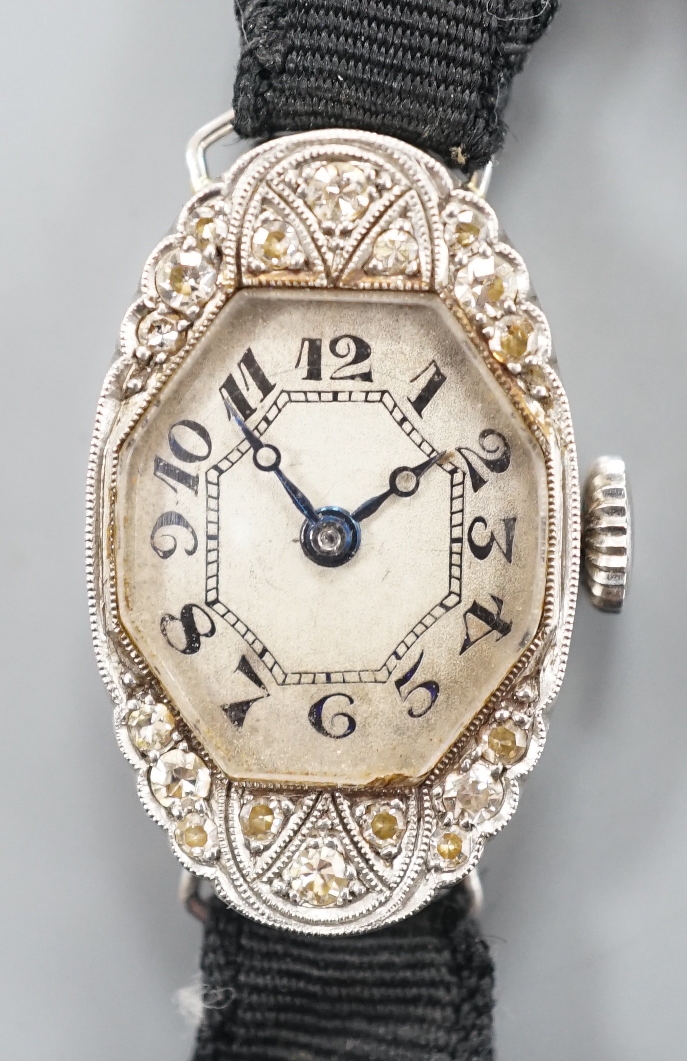 A lady's white metal (stamped platine) and diamond set oval cocktail watch, on a black sash bracelet, gross weight 13.9 grams.